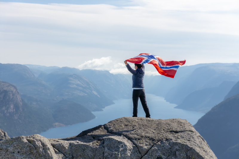 妇女挥舞挪威国旗与自然背景