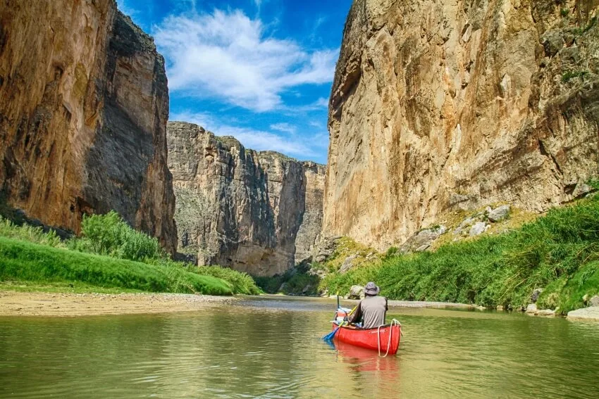 男人划独木舟在岩层之间的一条河