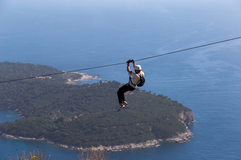 一名男子在亚得里亚海上用绳子坠海。杜布罗夫尼克附近的冒险景点。克罗地亚。